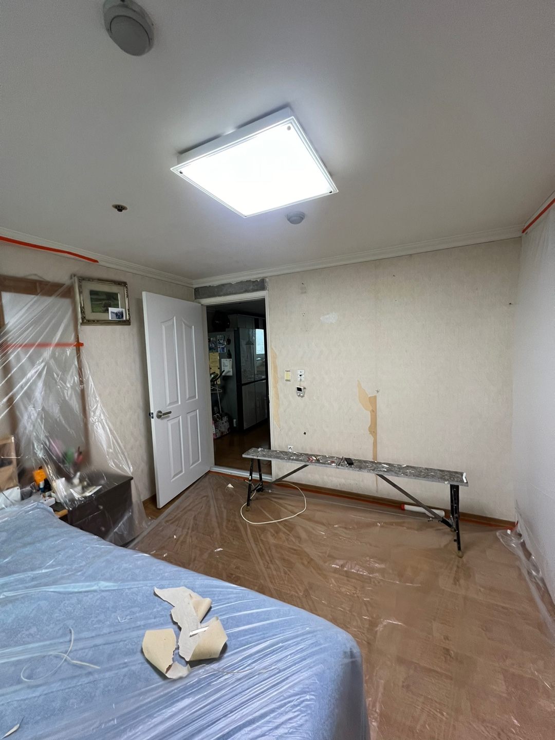 침대와 가구를 비닐로 덮어 보양한 뒤 작업대를 설치한 방